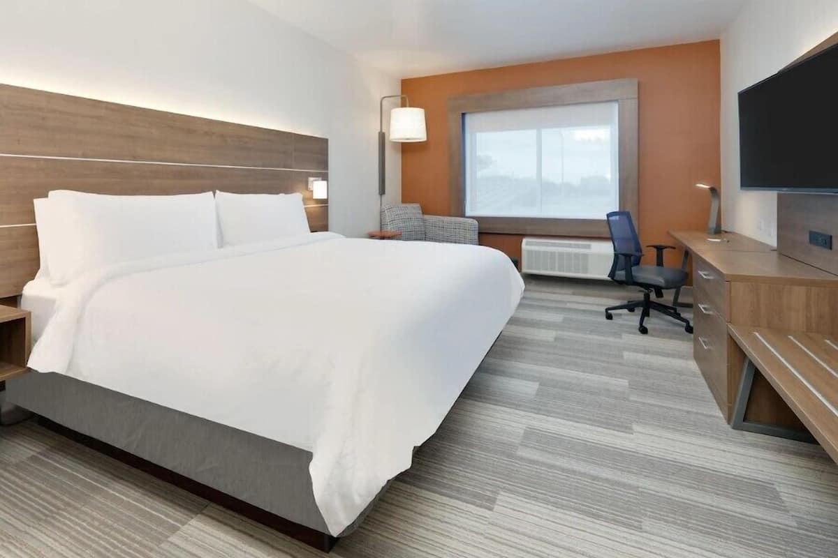 Habitación de hotel con una cama grande, un escritorio, una silla y un televisor.