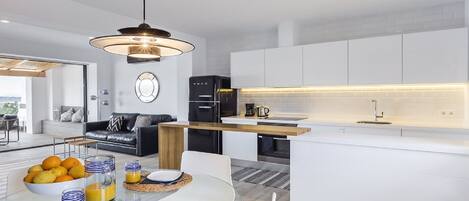 Una cocina moderna con armarios blancos, una isla integrada y un colgante de luz.