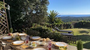 A wooden table set for a meal with plates, bowls, and cutlery, overlooking a scenic landscape with trees and a clear sky. - VILLA SECRET PARADISE COSTA BRAVA
Panoramic views & relax just 12m from beaches (Lloret de Mar)