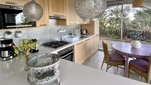 A modern kitchen with wooden cabinets, a gas stove, a sink, and hanging pendant lights. - VILLA SECRET PARADISE COSTA BRAVA
Panoramic views & relax just 12m from beaches (Lloret de Mar)