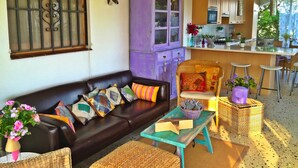A cozy living room with a dark leather sofa, colorful cushions, a woven coffee table, and a purple cabinet. - VILLA SECRET PARADISE COSTA BRAVA
Panoramic views & relax just 12m from beaches (Lloret de Mar)