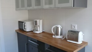 Eine Küchenzeile mit Toaster, Kaffeemaschine und Wasserkocher auf der Arbeitsfläche.