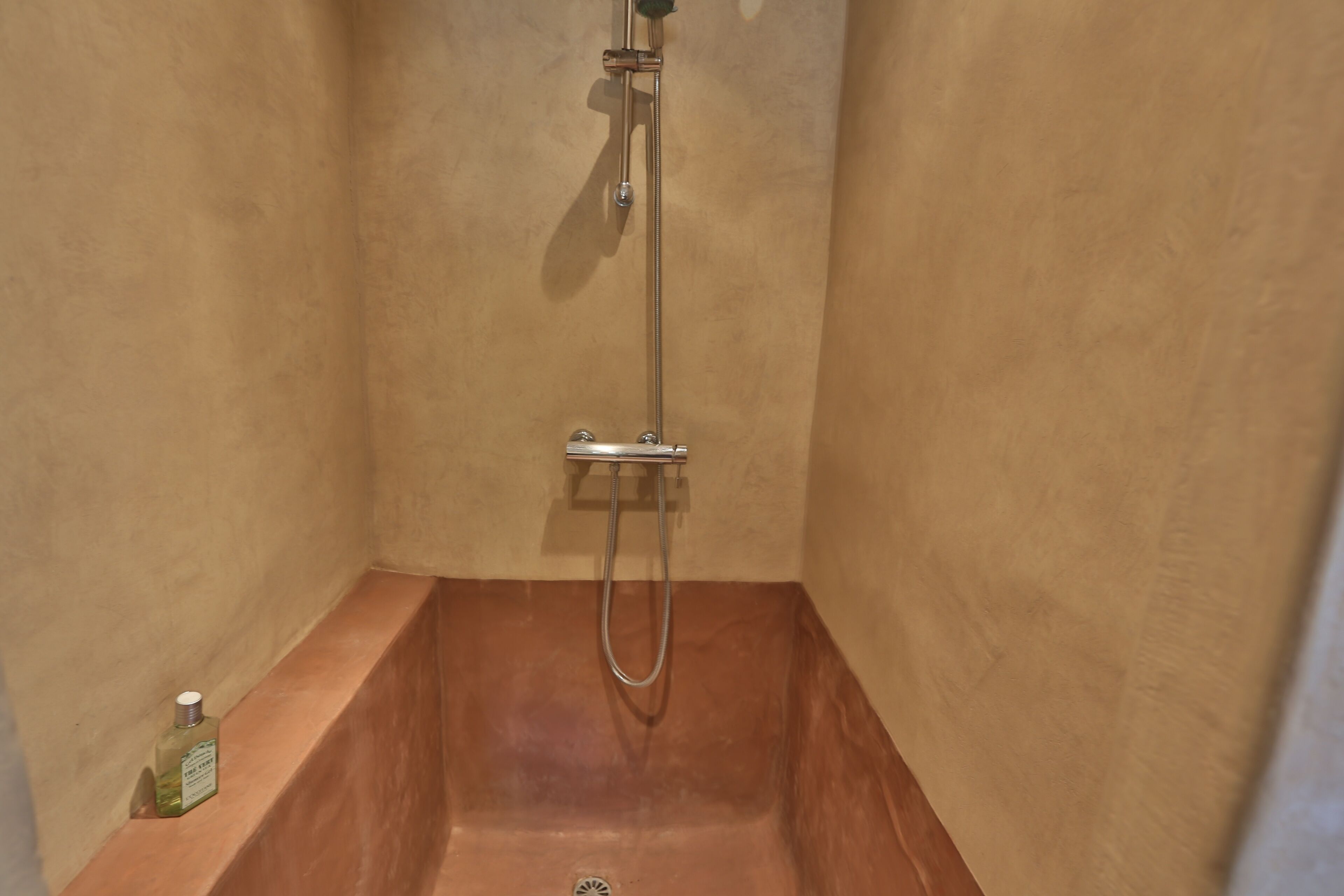 A small, enclosed shower area with a built-in sink and a handheld showerhead.