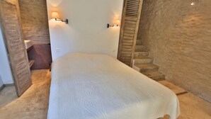 Een slaapkamer met een bed, een houten trap en een wandlamp.