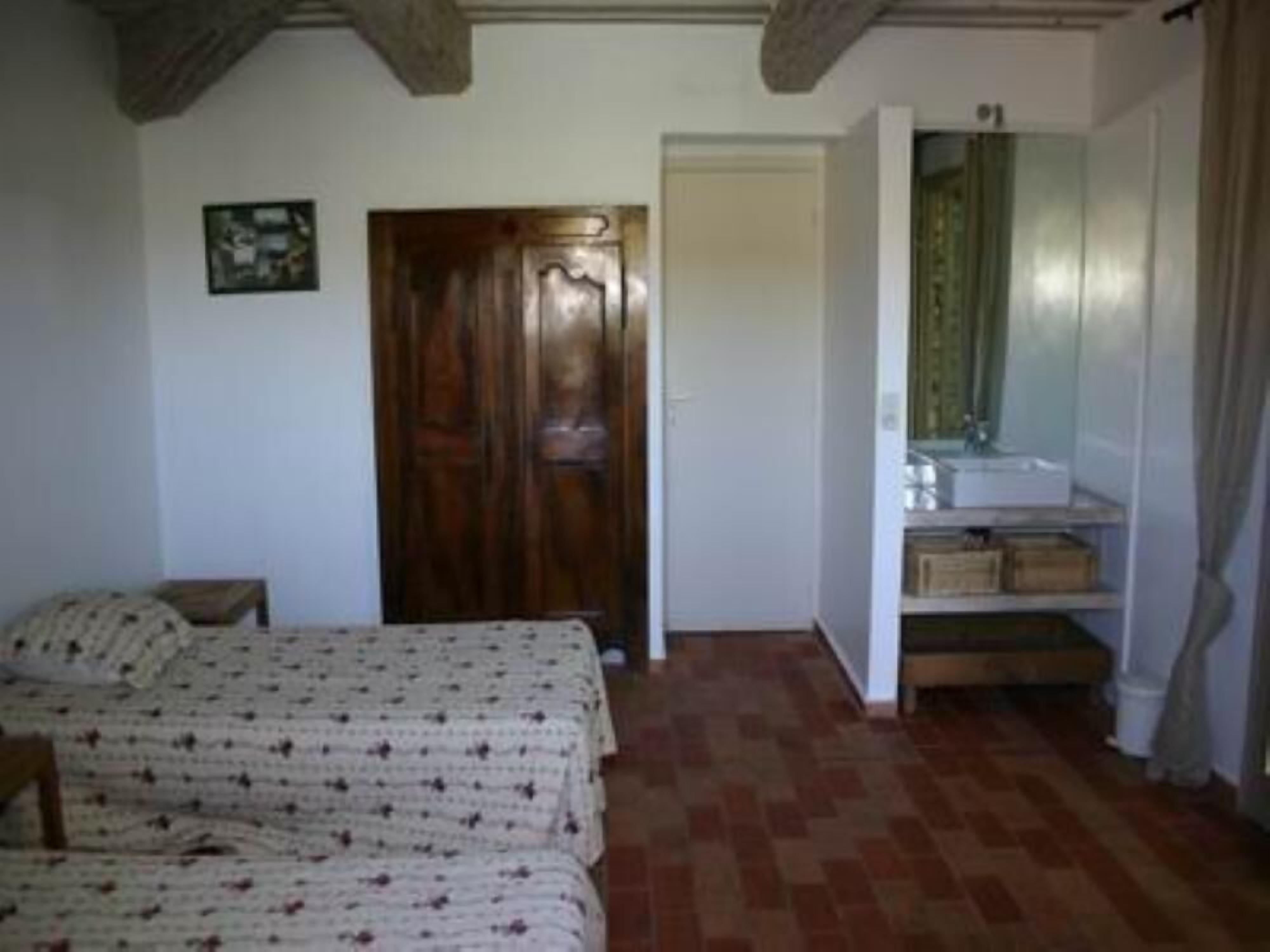 Una camera da letto con un letto, una porta in legno, un bagno con lavandino e specchio, e un pavimento piastrellato.