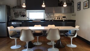 Una cocina moderna con una isla central, iluminación colgante y un comedor con cuatro sillas.