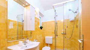 Une salle de bain moderne avec une douche à parois de verre, un lavabo blanc et des toilettes.