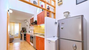Une cuisine de taille réduite, dotée d’armoires en bois, d’un réfrigérateur en acier inoxydable et d’un four à micro-ondes.