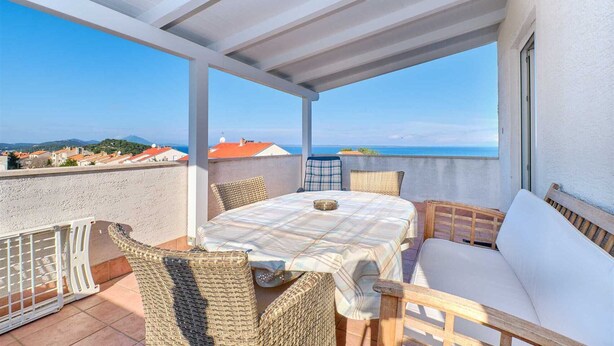 Un espace extérieur abrité, avec une table et des chaises, offrant une vue sur la côte.