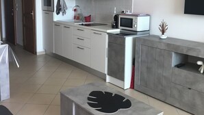 A modern kitchen with white cabinets, a microwave, and a built-in oven. There is a grey countertop with a black decorative object on it.