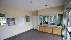 A spacious room with a large window, a reception desk, and a bulletin board with notices. - Scottish Inn & Suites (Baytown)