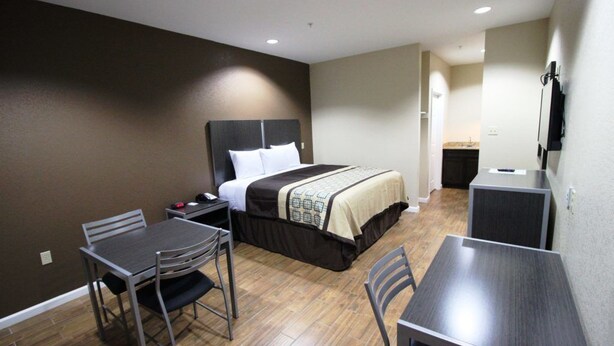 A hotel room with a bed, a desk, and a chair. - Scottish Inn & Suites (Baytown)