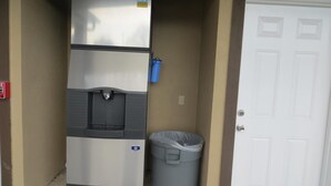 A compact kitchenette with a refrigerator, a water dispenser, and a trash bin. - Scottish Inn & Suites (Baytown)