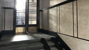 A staircase with a handrail, a door with a frosted glass panel, and a wall with a tiled pattern.