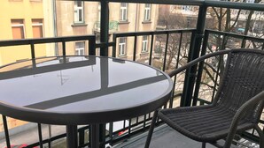 A balcony with a round table and a wicker chair.