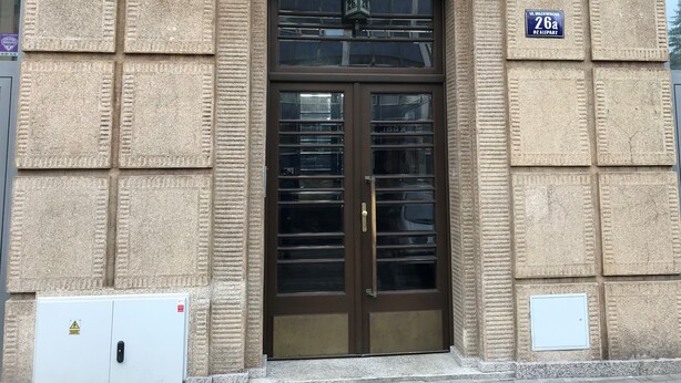 A building entrance with a double door, a sign above the door, and a utility box to the left.