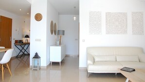 A modern living room with a white sofa, a dining area with a table and chairs, and decorative wall art.
