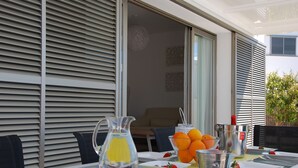 A dining table set with a pitcher, bowls of fruit, and a metal bucket.