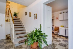 Staircase leads to an upper level, flanked by potted plants and framed pictures.