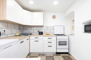 A modern kitchen with white cabinets, a gas stove, and a microwave.