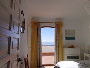 A bedroom with a view of the sea, a bed, a nightstand, and a door with a keyhole. - Apartment in quiet area with good sea views, community pool. (Nerja)