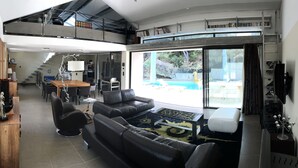 A spacious living room with a large sofa, a coffee table, and a dining area with chairs and a table. - At the top of the village, magnificent view of Mt Ventoux, private heated swimming pool (Bédoin)