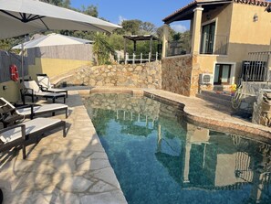 A swimming pool with lounge chairs and a pergola, surrounded by stone walls and a wooden fence. - Prestigious Villa Santa Pazienza with pool (Castiadas)