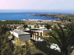 Un complejo turístico frente al mar con villas modernas, vistas al océano y exuberante vegetación.