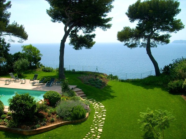 A landscaped garden with a swimming pool, lounge chairs, and a view of the sea. - Magnificent house with private heated pool and amazing panoramic sea view (La Garde)