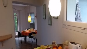 A dining area with a table set for two, a kettle, condiments, and a window with a view.