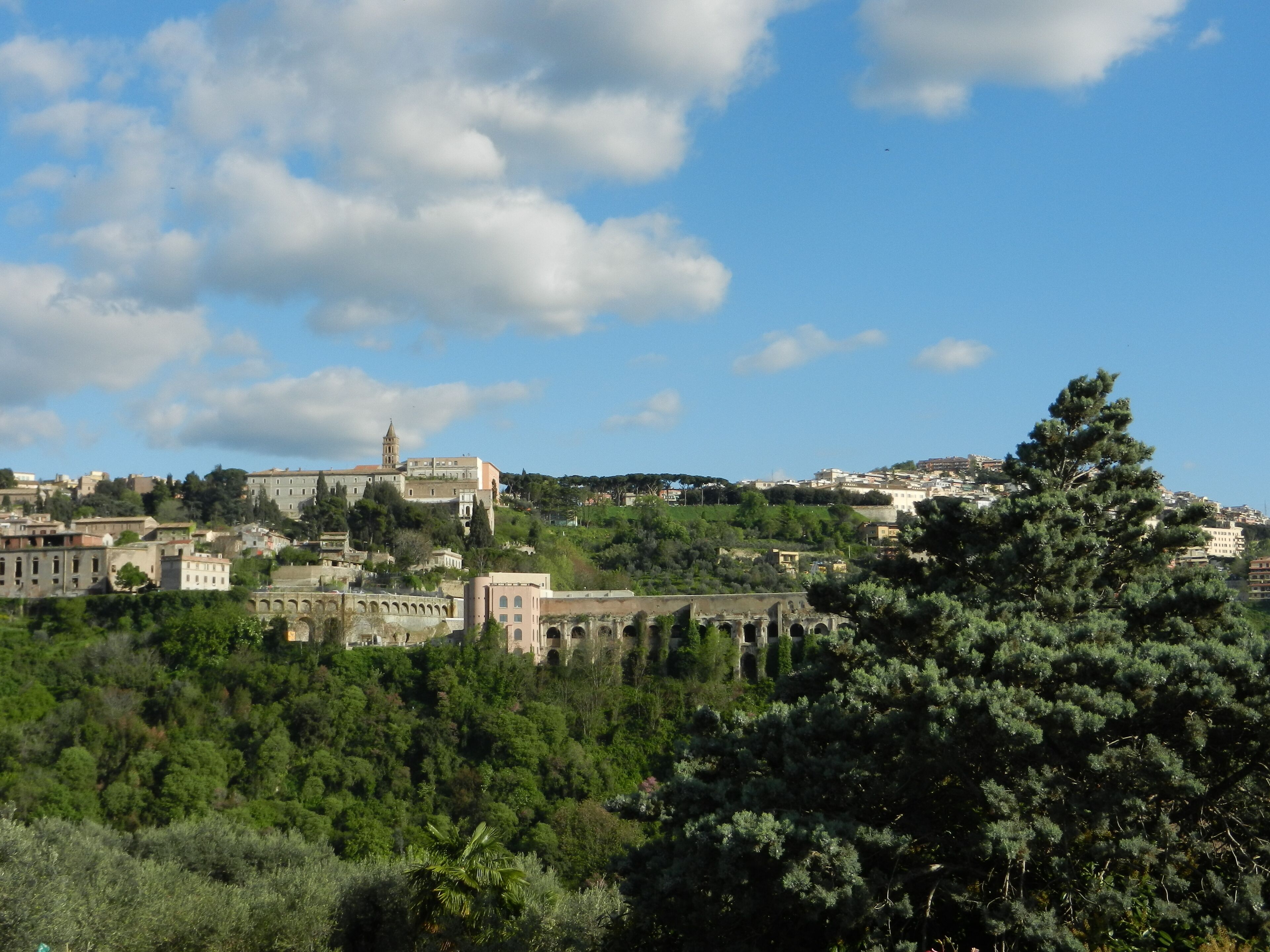 A historic town with a prominent church on a hill, surrounded by lush greenery and a clear sky.