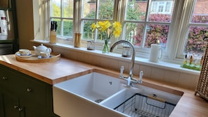 A kitchen with a double sink, wooden countertop, and a window with a view of greenery and buildings. - Peaceful, Picturesque, Stylish Property in Benenden Converted Barn (Cranbrook Rd)