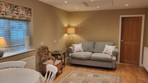 A cozy living room with a sofa, a table, and a chair. - Peaceful, Picturesque, Stylish Property in Benenden Converted Barn (Cranbrook Rd)