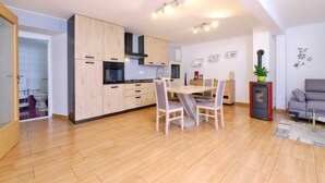 Une cuisine moderne avec des meubles en bois, un coin repas avec une table et des chaises, un canapé et un petit radiateur.