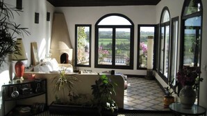 A cozy living room with a fireplace, large windows, and a view of the countryside. - House with character (Azemmour)