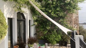 An outdoor dining area with a table set for four, surrounded by chairs, on a terrace with a view of a building and greenery. - House with character (Azemmour)