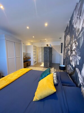Une chambre à coucher comprenant un lit, une armoire, un miroir et un escalier menant à une autre pièce.