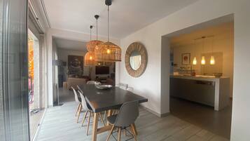 Un espace repas moderne avec une table en bois foncé, des chaises gris clair et un luminaire suspendu au centre.