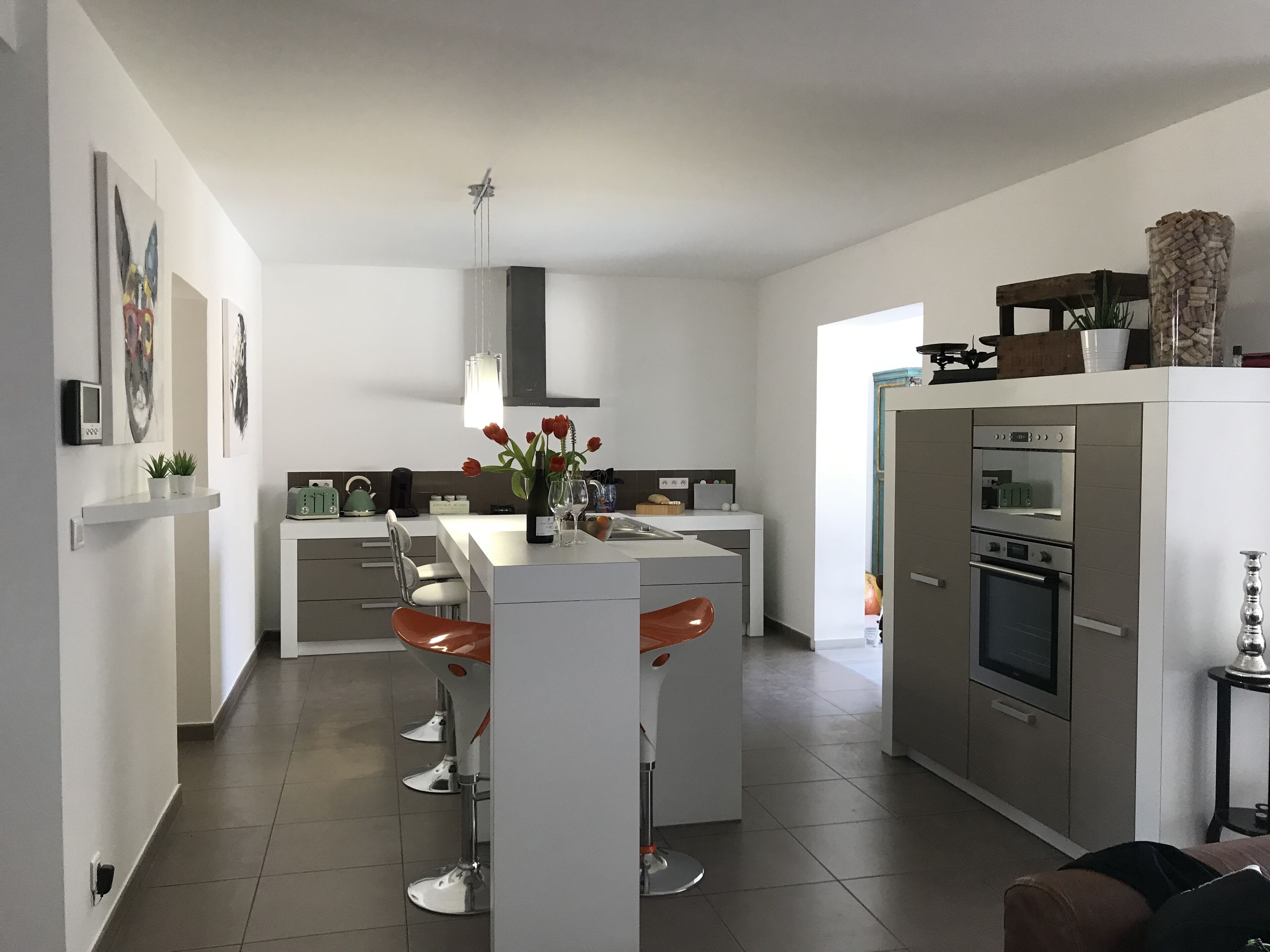 Une cuisine moderne dotée d’un îlot central, de meubles blancs et d’appareils électroménagers en acier inoxydable.