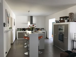 Une cuisine moderne dotée d’un îlot central, de meubles blancs et d’appareils électroménagers en acier inoxydable.