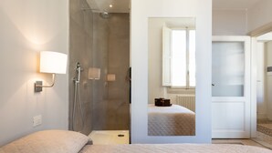 A modern hotel room with a bed, a shower, and a view of a cityscape through a window. - Loft with a panoramic terrace overlooking the rooftops of Florence (Firenze)