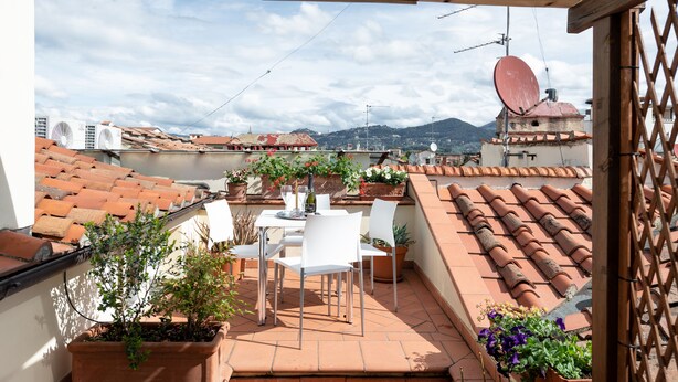 A terrace with a table and chairs, potted plants, and a view of the cityscape and mountains. - Loft with a panoramic terrace overlooking the rooftops of Florence (Firenze)