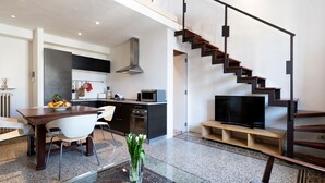 A modern living space with a dining area, kitchen, and a staircase leading to an upper level. - Loft with a panoramic terrace overlooking the rooftops of Florence (Firenze)
