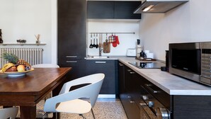A modern kitchen with dark cabinets, a stainless steel range hood, a microwave, and a fruit bowl on the counter. - Loft with a panoramic terrace overlooking the rooftops of Florence (Firenze)