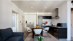 A modern living room with a dark sofa, a glass coffee table with a vase of flowers, and a dining area with a wooden table and white chairs. - Loft with a panoramic terrace overlooking the rooftops of Florence (Firenze)