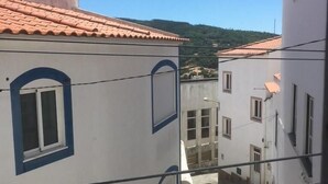 Une rue étroite bordée d’immeubles aux façades blanches et aux encadrements de fenêtres bleus, qui mène à une colline.