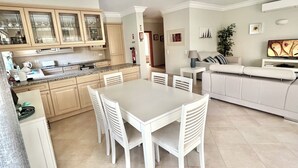 Eine moderne Küche mit weißen Schränken und einem Essbereich mit weißem Tisch und Stühlen.