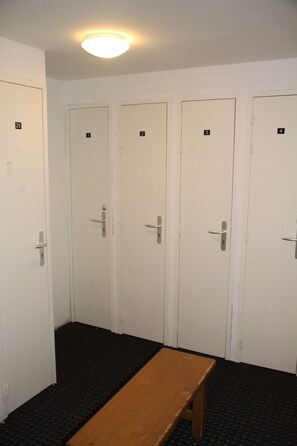 A row of white doors with numbers, a bench, and a black patterned floor.