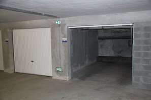 A parking garage with concrete walls, a white door, and a metal gate.