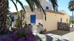 A villa with a stone wall, blue shutters, and a gravel driveway. - Villa ideal for families with pool and bbq near the sea in Pollença and WIFI (Pollença)